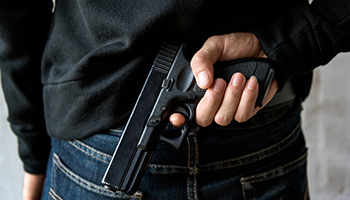 Back view man reaching hand gun attached